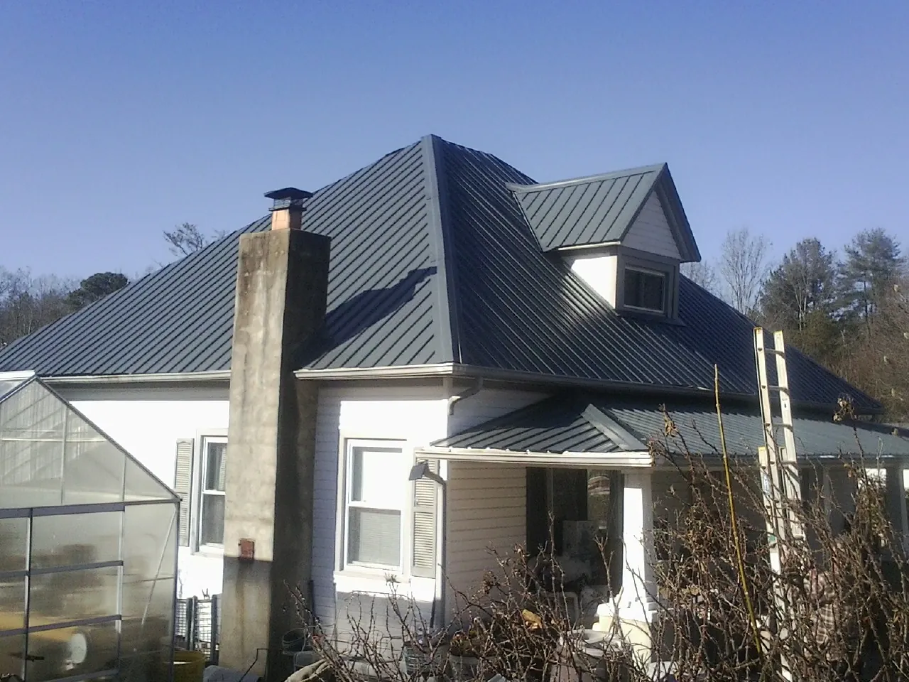 Dark blue standing seam metal roof on a white farmhouse with dormer — Slate & Tile Roof Repair by Roofing Brothers in Solway