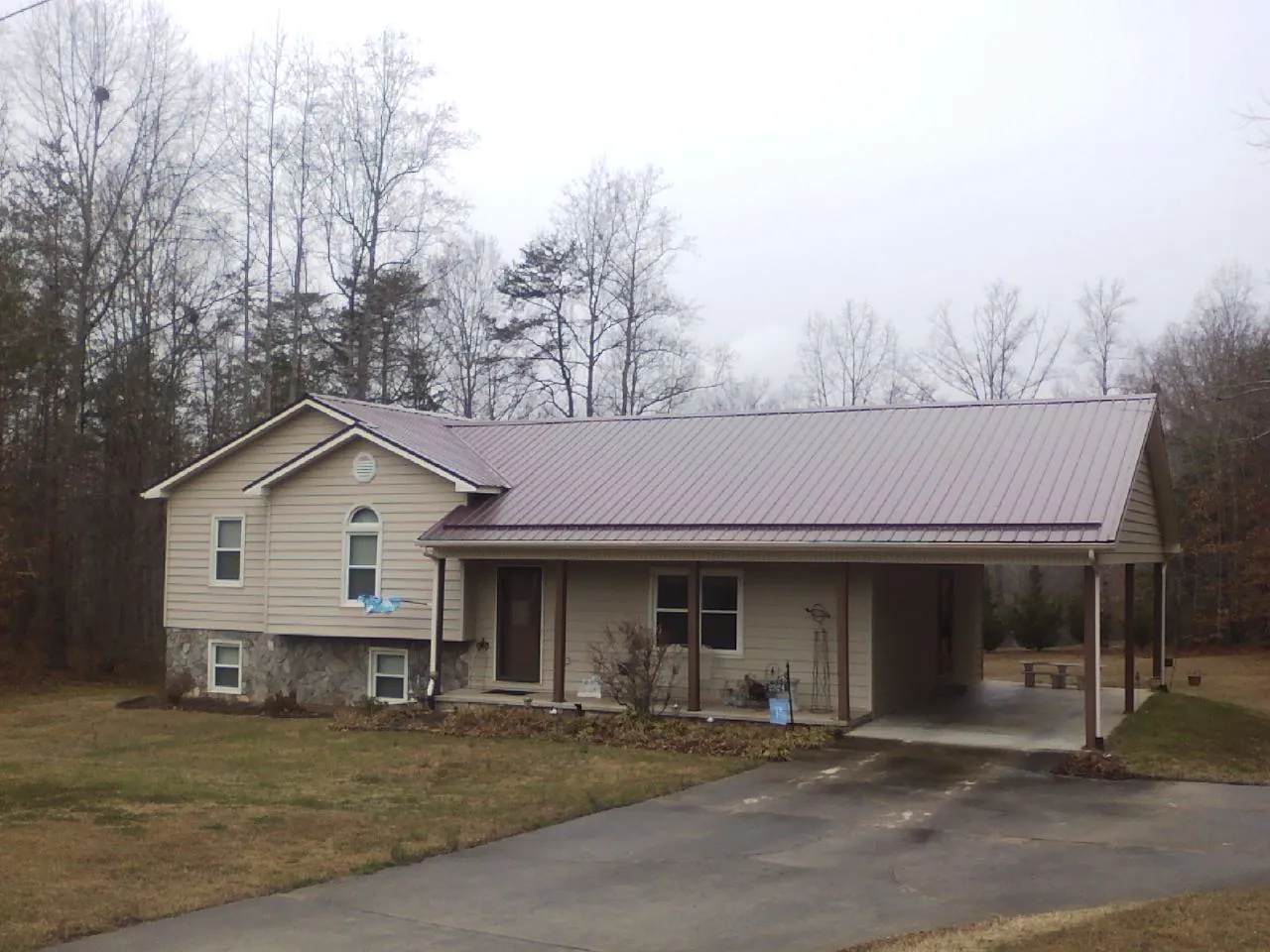 Burgundy metal roof on a tan split level home with an attached carport in Solway