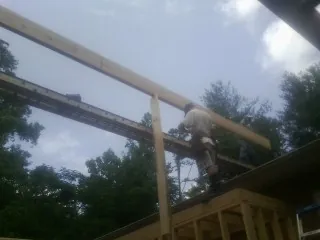 Carpenter setting a ridge beam over a new addition frame — Ice Dam Removal by Roofing Brothers in Solway