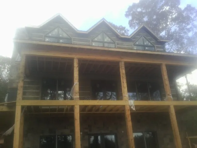 Dormers and porch framing on a large log home under construction — Roof Coating work by our crew in Solway