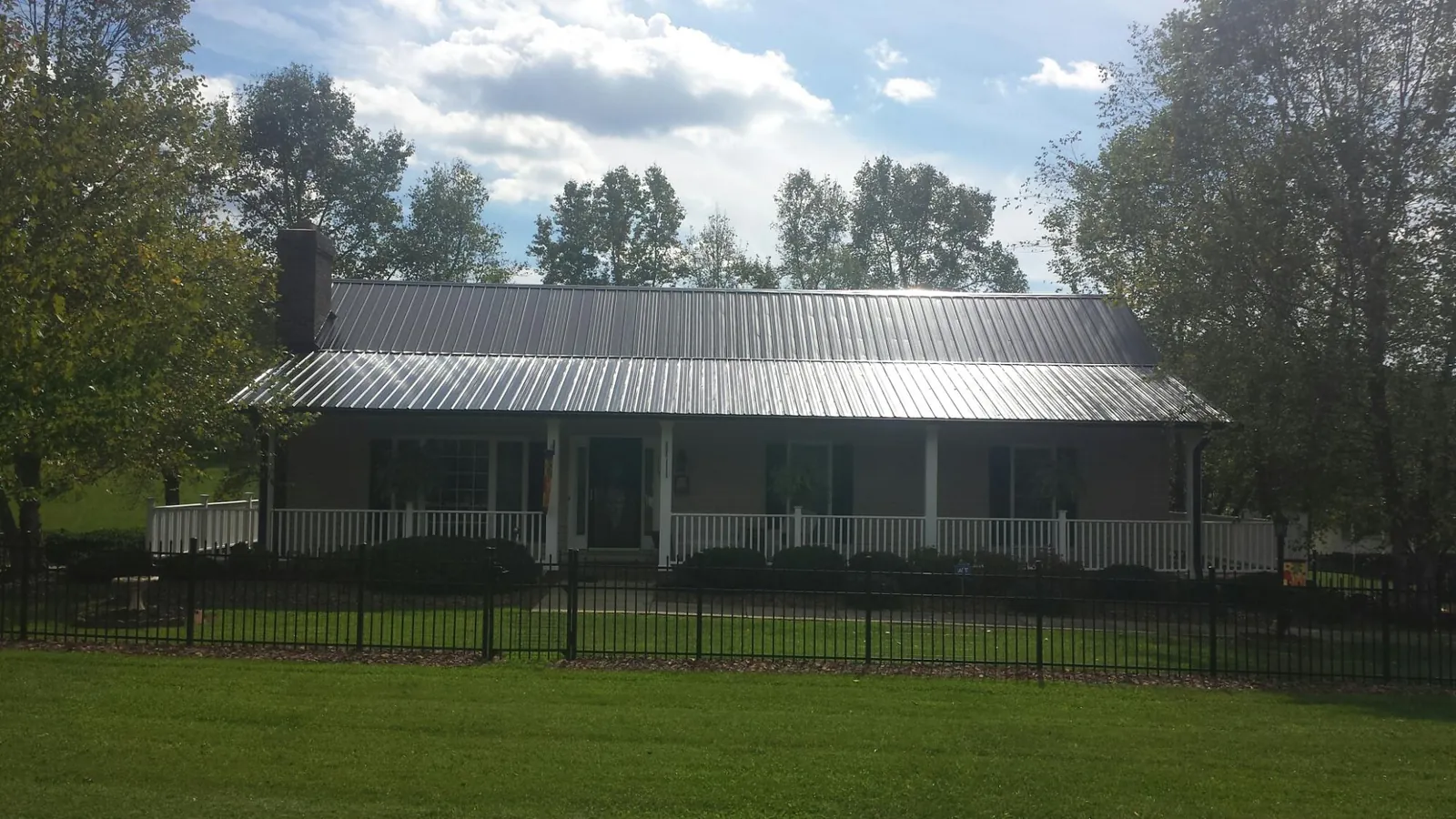 Gray metal roof on a brick ranch with a full width front porch — Gutter Guard Installation work by our crew in Solway