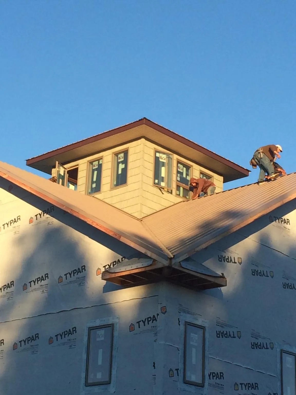 Roofers working around a rooftop cupola on a new metal roof at sunset — Roof Waterproofing in Solway by Roofing Brothers